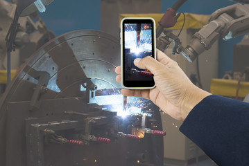 Hand holding phone taking photo of welder Industrial automotive