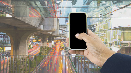 Hand holding the phone over cityscape background concept.