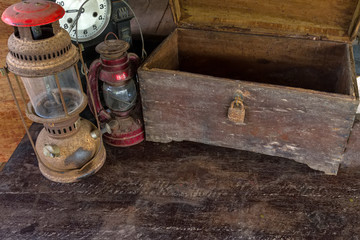 Vintage oil lamp ,old wooden box and alarm clock on old wooden touch-up in still life concept,dark tone.