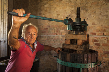 Old winemaker farmer working on a traditional wine press 