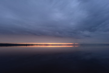 Sunset in the sky dark on the surface of the deep blue water