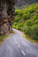Mountain road between cliffs and wooded valleys