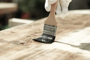 Painter painting wooden surface, protecting wood