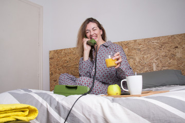 He is smiling woman on the phone while having breakfast in bed