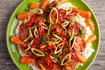 takeawy classic pork on rice with fried in sticky souce carrots, sprinkle of chillie and spring onion.