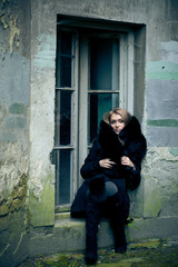 Woman enveloped in black fur sits in the window