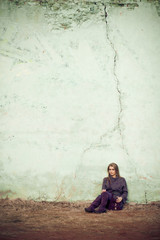 Lonely lady in violet sits before a white wall