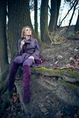 Tired blonde in violet rests on the ground in park