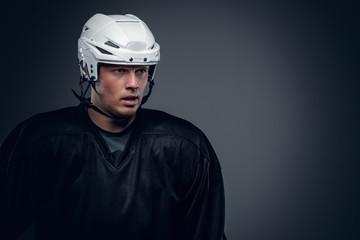 Portrait of hockey player on grey background.