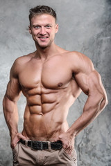 Fototapeta premium Handsome athletic fitness muscular man posing on a gray backgrou