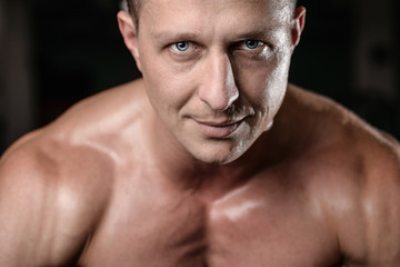 Fototapeta premium Handsome athletic fitness man posing and trains in the gym.