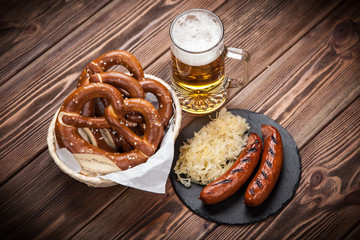 Pretzels, bratwurst and sauerkraut on wooden table