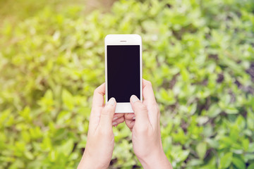 Women hand holding using mobile smart phone in the park