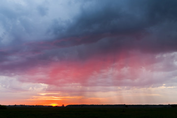 Naklejka na ściany i meble Sunset on a background of storm clouds. Bad weather, rainy weather. 