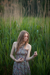 Thin lady with white skin stands among green grass