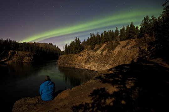 Person watching nothern lights over Miles Canyon, Whitehorse, Yukon, Canada.