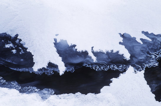 Rocky mountains, ice and snow frame moving water in creek, British Columbia, Canada.