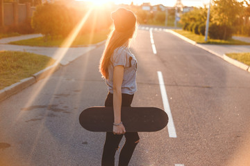 Beautiful and fashion young woman posing with a skateboard on the street