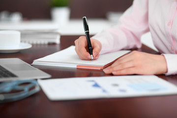 Closeup of a business woman writing in a notebook