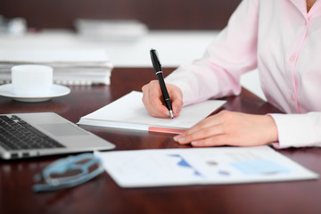 Closeup of a business woman writing in a notebook