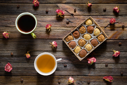 Sweet food pattern. Box of chocolate truffles, coffee beans, dry rose flowers, cup of black coffee and green tea on wooden backdrop. Top view. Valentines day, mothers day concept. Flat lay