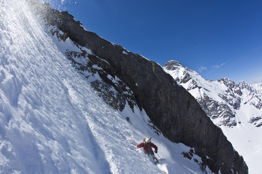 A male backcountry skier on tele skis descends a steep couloir with a unique limestone arch in it. Mt. French, Peter Lougheed Provincial Park, Kananaskis, AB