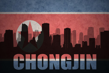 Fototapeta premium abstract silhouette of the city with text Chongjin at the vintage north korea flag background