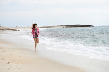 beautiful girl with colorful windbreaker running on the beach