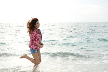 Fototapeta na wymiar beautiful girl with colorful windbreaker running on the beach