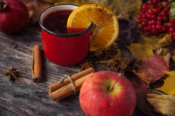 red cup of hot mulled wine in autumn among leaves