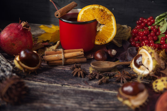 red cup of hot mulled wine in autumn among leaves