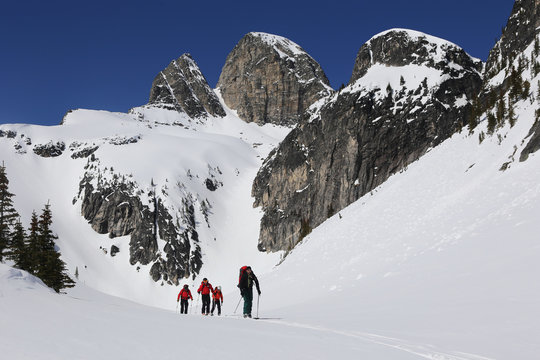 Small group of people backcountry skiing on the snowy summits of  Valhalla Provincial Park, British Columbia, Canada