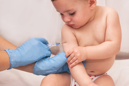 Close-up shot of pediatrician giving a one year baby girl intramuscular injection in arm