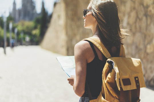 Hipster young girl with backpack using and looking at map. Said view tourist traveler enjoying on background panoramic city. Person visiting the sights Barcelona in holiday. Mockup