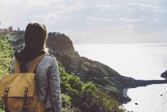 Hipster young girl with backpack enjoying sunset on seascape on peak mountain. Tourist traveler on background valley landscape. Hiker looking sunlight ocean in trip holiday in basque island