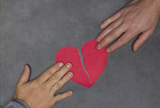 two people tearing paper red heart in half