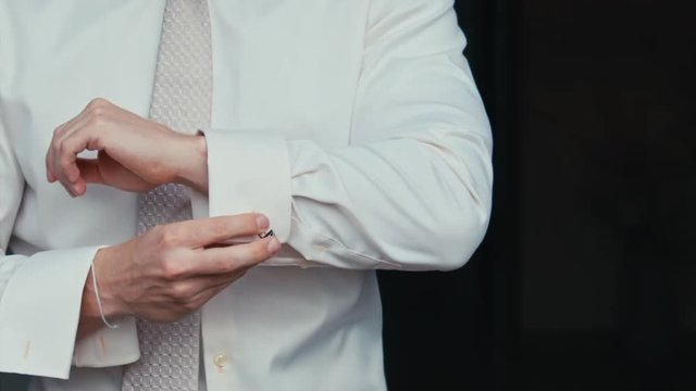 man buttons cuff link on the shirt