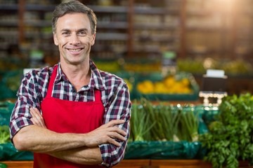 Smiling male staff standing with arms crossed in organic section - Powered by Adobe