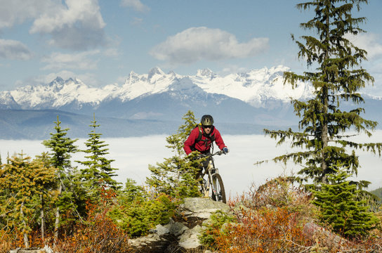 A mountain biker rides in front of the Valhalla Mountains on a trail called Vallelujah, Nelson, British Columbia