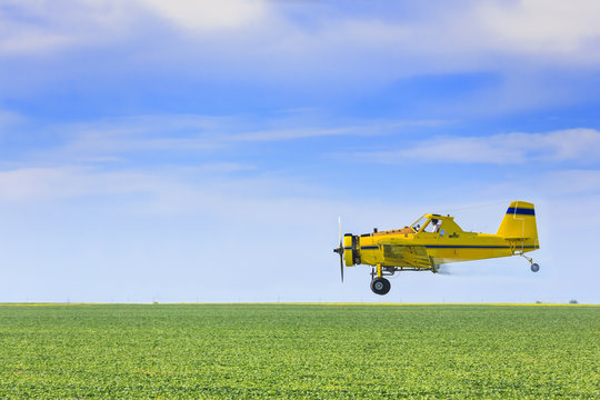 Crop duster airplane spraying farm field
