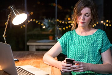 Businesswoman using mobile phone at her desk