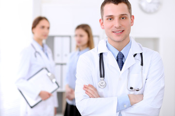 Fototapeta premium Friendly male doctor on the background with patient in hospital. High level and quality medical service concept.