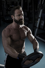Hombre con grandes músculos levantando peso mientras entrena en el gimnasio. Ponerse en forma.
