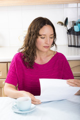 Upset woman with documents in kitchen