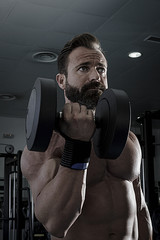 Hombre con grandes músculos levantando peso mientras entrena en el gimnasio. Ponerse en forma.