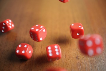 Several rolling red dice fall on a table