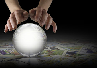 Crystal Ball Reading and Tarot Cards - Hands hovering over a large clear Crystal Ball on a dark...