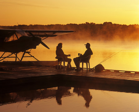 a couple relaxes on a float plane dock, Manitoba, Canada