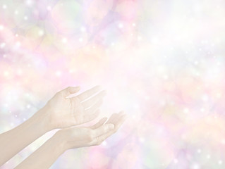 Sending Divine healing energy - female hands held out with a stream of white light on a soft pale pastel bokeh multicolored background with copy space all around 