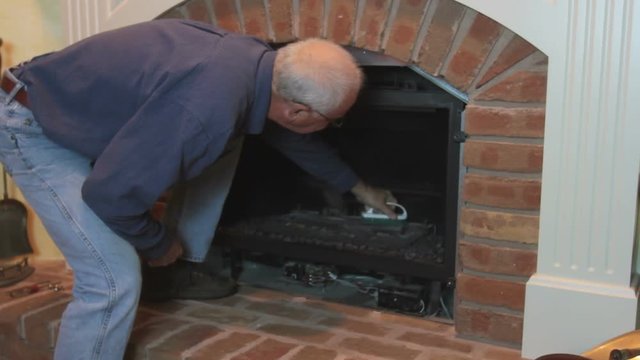 Man Cleaning And Maintaining Home Gas Fireplace.